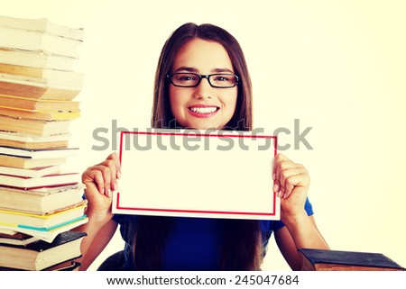 Beautiful young student woman wih stack of books and holding copy space.