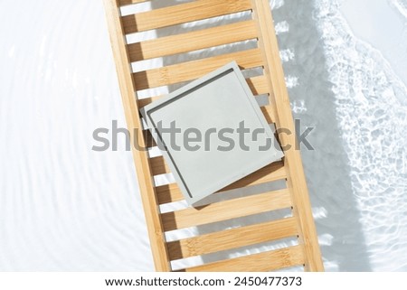 Beauty cosmetic product presentation flat lay scene made with empty square podium on a bath tray above the fresh water.