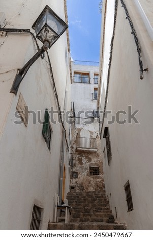 A narrow, steep stairway wedged between aged buildings in the bustling part of Eivissa town, Ibiza, Spain, captures the essence of Mediterranean urban life Royalty-Free Stock Photo #2450479667