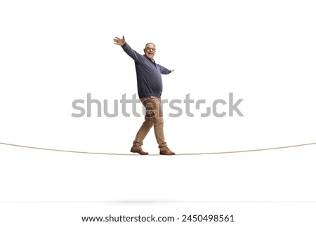 Full length shot of a mature man walking on a rope isolated on white background, keep balance concept