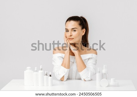 Gorgeous middle aged woman touching her perfect skin. Beautiful portrait of a 40-50 year old woman advertising anti-aging facial products, salon care, skin tightening, isolated on white background. Royalty-Free Stock Photo #2450506505
