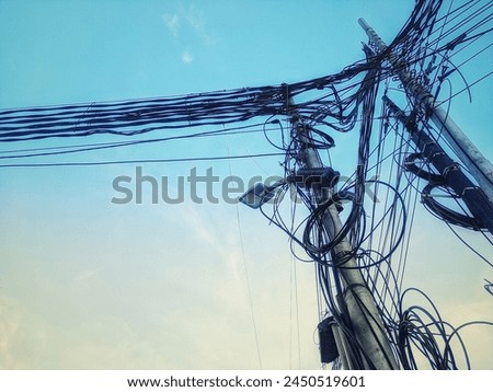 A view of the blue sky decorated with wires and power poles