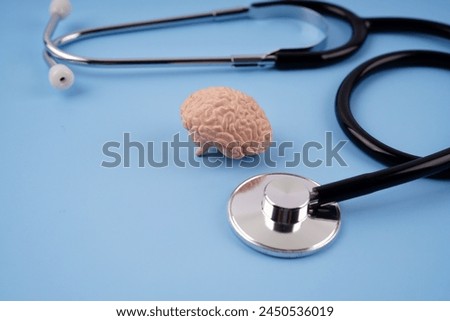 Health and medical concept. Mini humans brain replica and stethoscope arranged on a blue background.