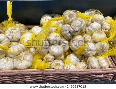 Dried garlic in a white mesh bag ready for sale. Garlic can lower cholesterol and maintain heart health.