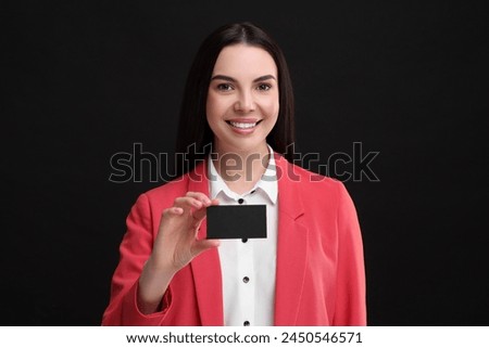 Happy woman holding blank business card on black background