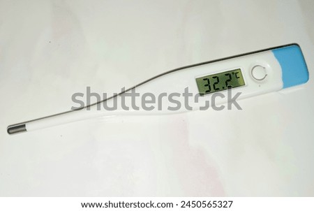 Electronic body thermometer that displays a healthy human body temperature of 32.2 degrees C (Celsius). Isolated on white background. Royalty-Free Stock Photo #2450565327