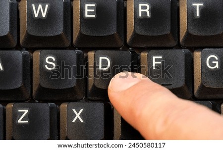 Man pressing a single D key on a modern laptop computer keyboard, finger pushing a key top view shot from above, one person. One single letter symbol input abstract concept, char, character value