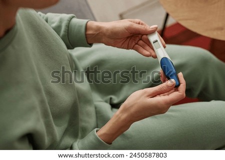 High angle close up of unrecognizable young woman holding pregnancy test with blank screen copy space