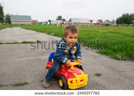 boy in a denim jacket sitting on a toy car, family and sports, toy car, spring, walk,  family sport, study	
