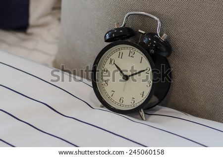 black classic alarm clock on bed in bedroom