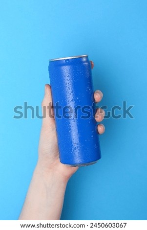 Woman with energy drink on light blue background, closeup