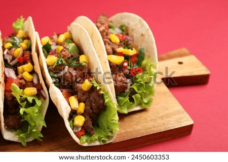 Delicious tacos with meat and vegetables on red table, closeup
