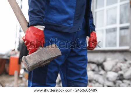 Man in uniform with sledgehammer outdoors, closeup