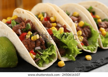 Delicious tacos with meat and vegetables on table, closeup