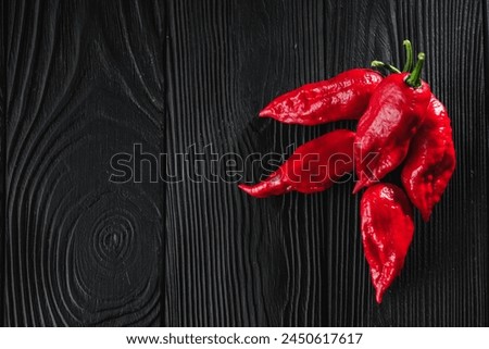 fresh red extra hot bhut jholokiya pepper on black wooden rustic background.