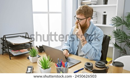 Confident young redhead man working joyfully on laptop at office, exuding confidence as business worker