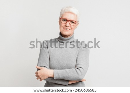 A senior European woman confidently posing with arms crossed portrays strength and assurance, contributing to the initiative Royalty-Free Stock Photo #2450636585