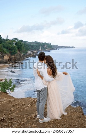 On the cliff, the married couple hugs affectionately
