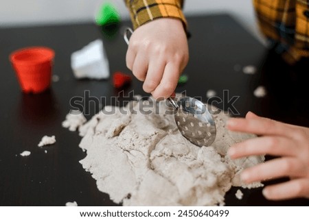 Cute boy plays in the sandbox at home. A child makes sand molds