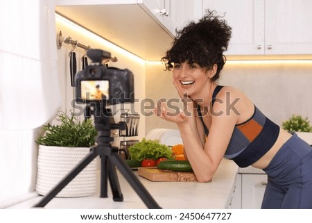 Smiling food blogger explaining something while recording video in kitchen Royalty-Free Stock Photo #2450647727