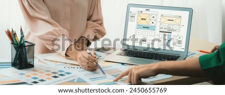 Cropped image of interior designer presents color from color swatches while laptop displayed website wireframe designs for mobiles app and website. Creative design and business concept. Variegated.