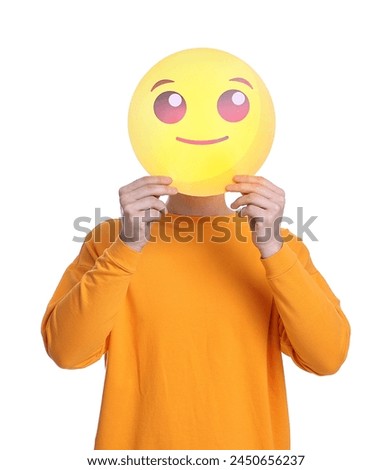 Man covering face with smiling emoticon on white background