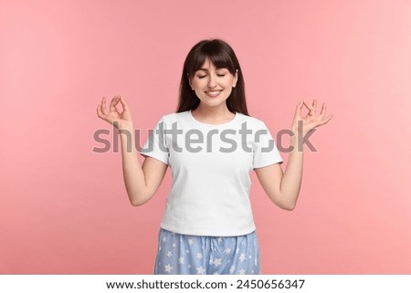 Woman in pyjama meditating on pink background