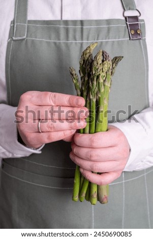 Green asparagus in the hands of a man. Bunch of ripe fresh asparagus. Healthy organic food. Cooking in home. Natural vitamins, raw ingredient for eating. Handpicked bio asparagus Royalty-Free Stock Photo #2450690085