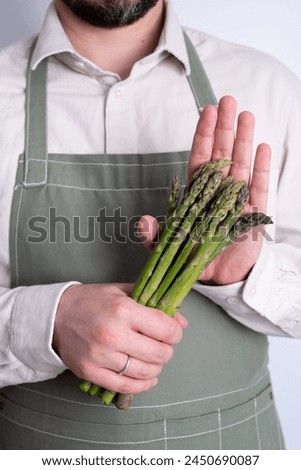 Green asparagus in the hands of a man. Bunch of ripe fresh asparagus. Healthy organic food. Cooking in home. Natural vitamins, raw ingredient for eating. Handpicked bio asparagus Royalty-Free Stock Photo #2450690087