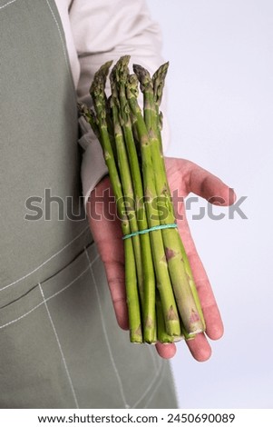 Green asparagus in the hands of a man. Bunch of ripe fresh asparagus. Healthy organic food. Cooking in home. Natural vitamins, raw ingredient for eating. Handpicked bio asparagus Royalty-Free Stock Photo #2450690089