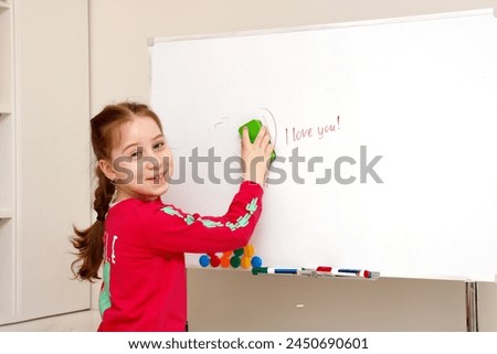 cute little girl erases the inscription i love you from the board.
