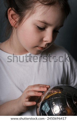 A little girl dreams of a trip while holding a globe in her hands. High quality photo