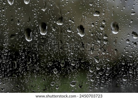Rainy background with water drops flowing down on window glass