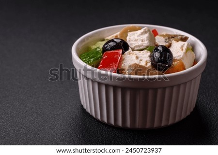 Delicious fresh juicy salad of sweet peppers, cheese, olives, tomatoes, cucumbers with salt and spices on a dark concrete background