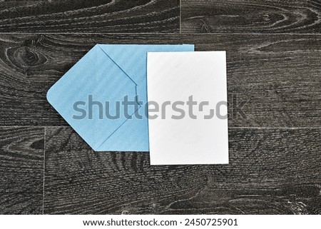 blue envelope with Blank paper with green palm leaf on wood - White paper sheet on a dark wooden texture 