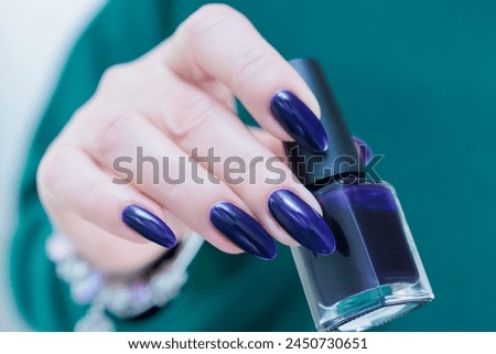 Female hand with long nails and a dark blue purple color nail polish