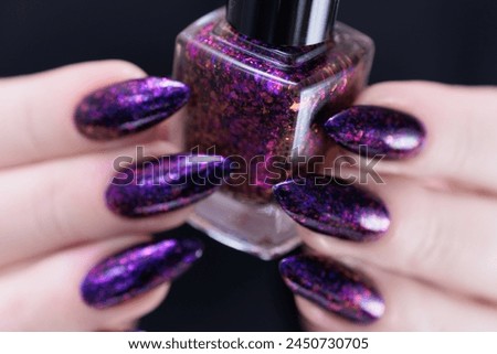 Female hands with long nails and dark purple manicure 