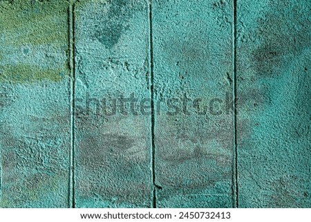 Dirty turquoise painted concrete wall with indented lines vertically and green mildew stains. Background and wallpaper texture.