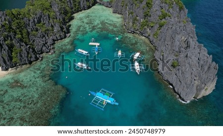 Aerial view of tropical island in Philippines. Boats in blue lagoons and lakes, white sand beach, rocks cliffs mountains and coral reef