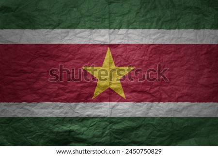 colorful big national flag of suriname on a grunge old paper texture background