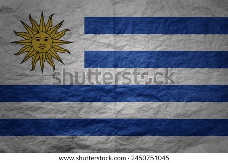 colorful big national flag of uruguay on a grunge old paper texture background