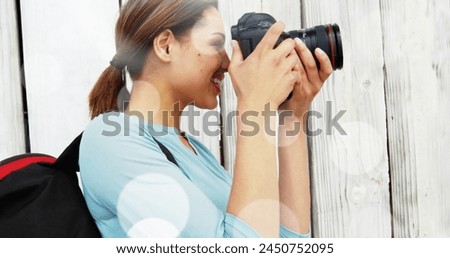 White spots floating against caucasian female photographer clicking pictures with digital camera. world photo day awareness concept