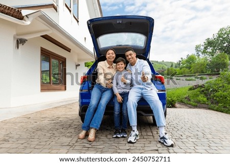Joyful family, posing next to their luxury car outdoors outside the house, smiling at the camera. Car leasing and ownership Royalty-Free Stock Photo #2450752711