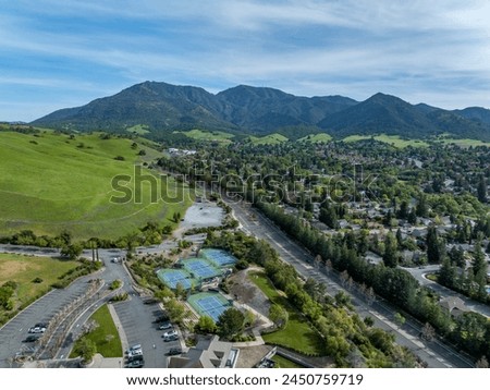 Drone photos over the Oakhurst neighborhood in Clayton, California with green hills, golf course and homes.