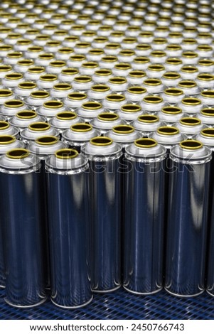 Cans, group of many empty valveless aerosol cans in manufacturing process, aerosol manufacturing Royalty-Free Stock Photo #2450766743