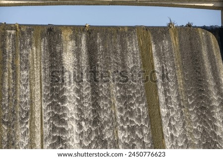 A dam is a barrier built over a river or stream, whose purpose is to impound water in the river bed  Royalty-Free Stock Photo #2450776623