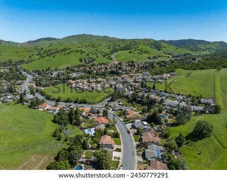 Drone photos over the beautiful city of Clayton, California with green hills, blue sky and homes