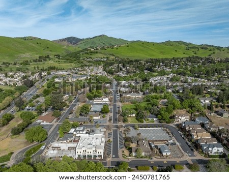 Drone photo over downtown Clayton, California with a blue sky, green hills and real estate