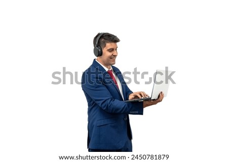 businessman in a suit diligently working on his portable laptop, which he holds with his hands. Accompanied by headphones, he embodies productivity and focus in corporate environment white background