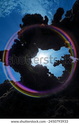 A full-circle rainbow is created in this image when the sunburst seen through an opening in the coral reef hits the dome port of the camera.